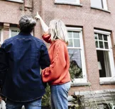 Stel wijst naar woning - De Hypotheker